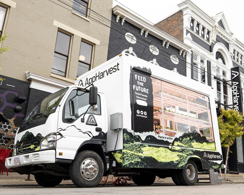 A truck with a miniature greenhouse inside sits in front of AppHarvest's offices