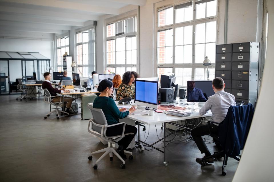 Personas que trabajan en una oficina de planta abierta muy concurrida