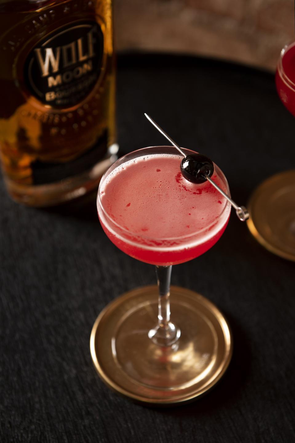 cupid cherry cocktail with cherry and bourbon bottle