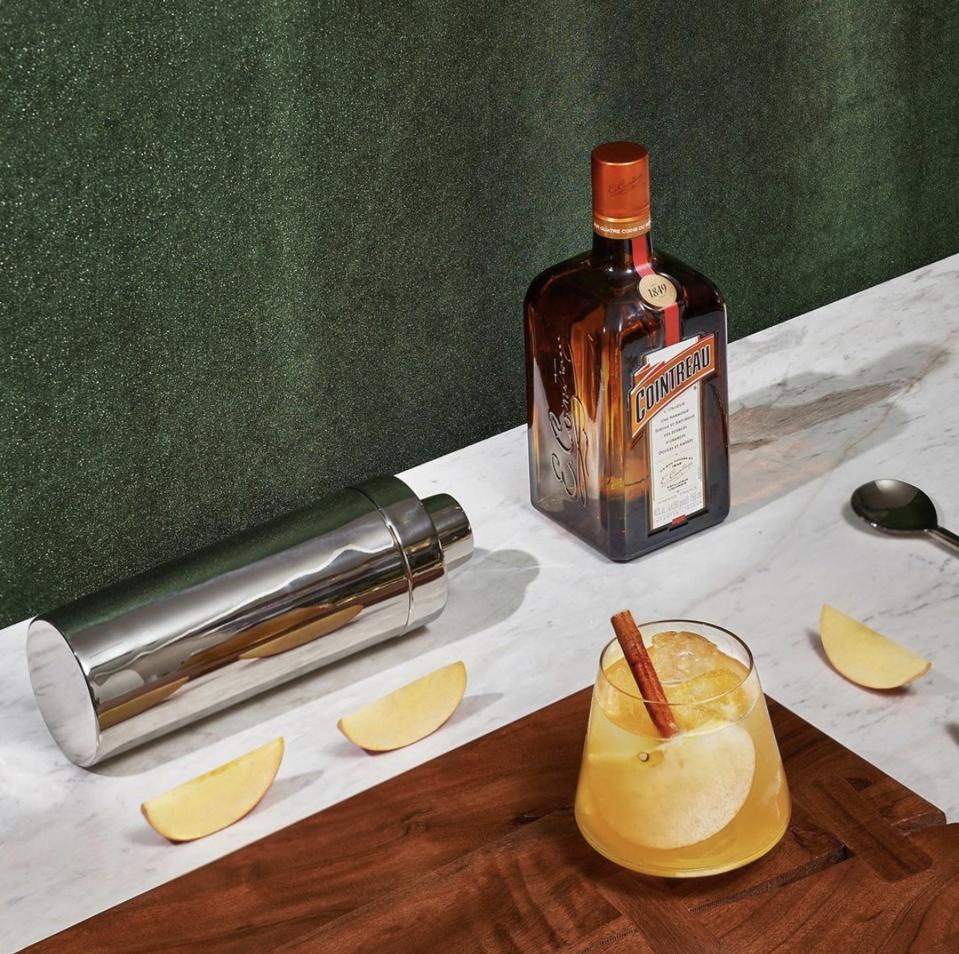 cointreau, apples, margarita, shaker and spoon artfully arranged on wooden tray