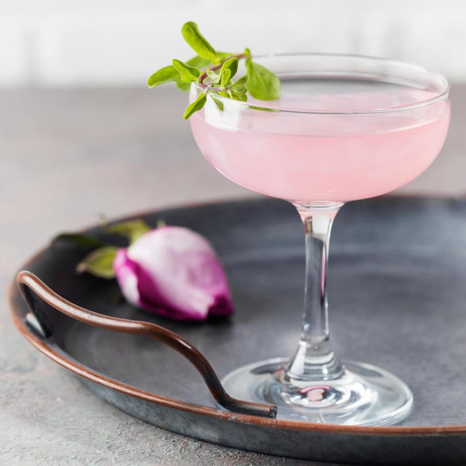 a pink vodka cocktail with a rose on a platter