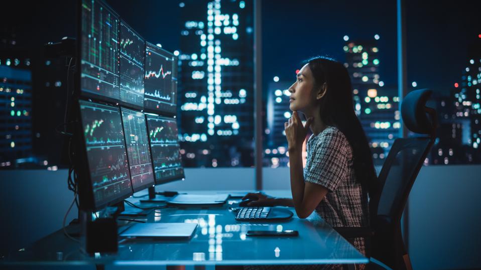 Financial Analyst working on multi-monitor workstation with real-time stocks, commodities and exchange market charts.