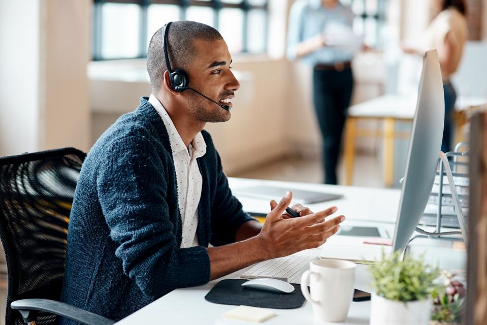 Shot of a young businessman wearing a headset while working on a computer in an office