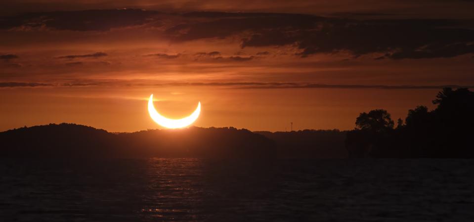 Solar Eclipse at sunrise over lake