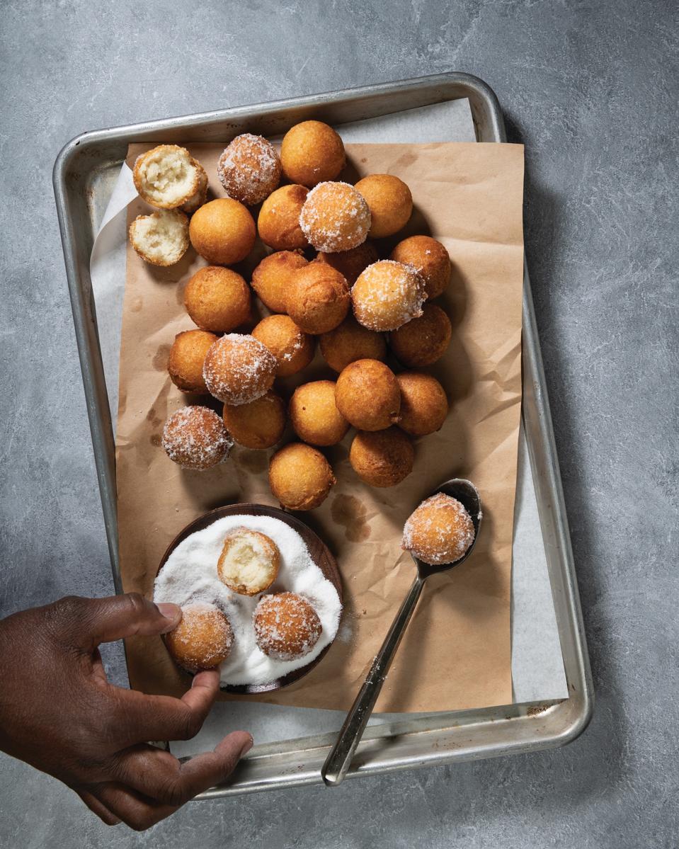 In the photo are Vitumbua and sugar on a sheet pan. They are fried dough balls rolled in sugar popular in the Congo. This family recipe is from Eli's employee Elias Kasongo and can be found in Eli's Cheesecake Cookbook.