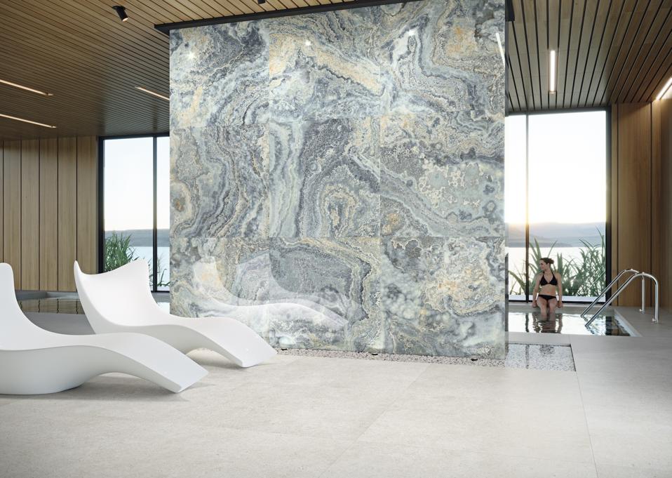 Blue marble slabs create a tall tile wall between a pool and lounge area.