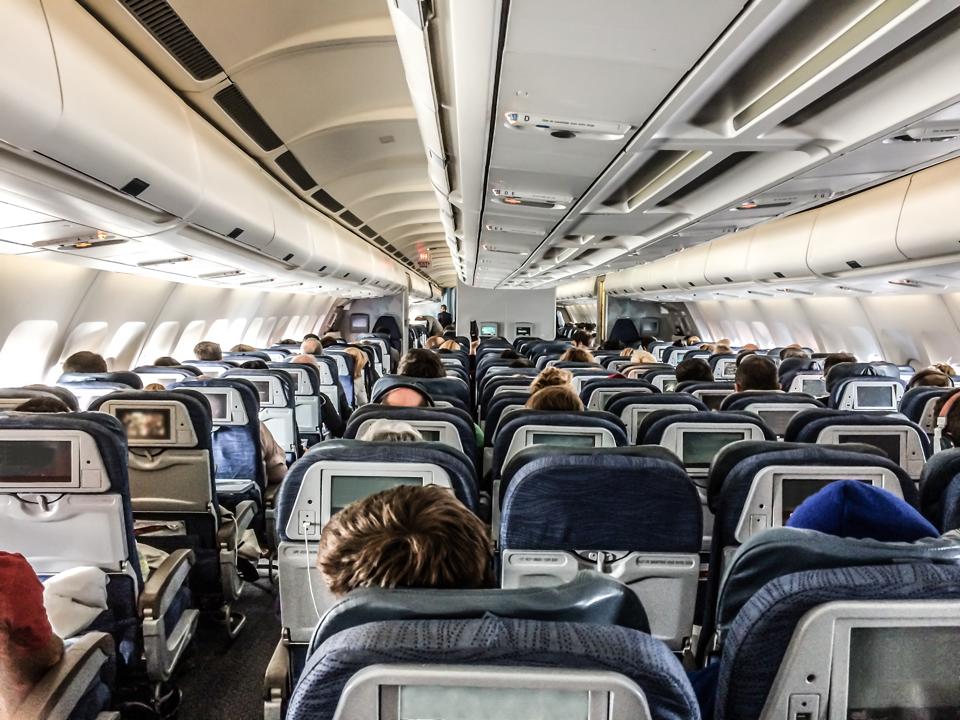 Passengers in a plane seen from behind above seats