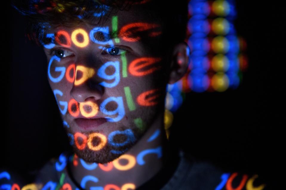 The Google logo is projected onto a person's face.