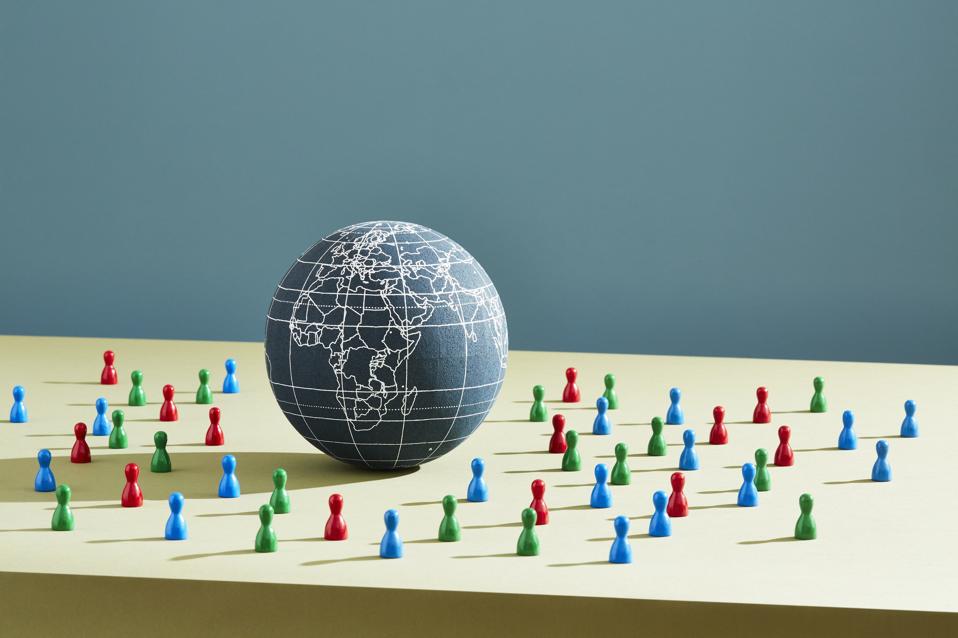 A world globe surrounded by people figurines
