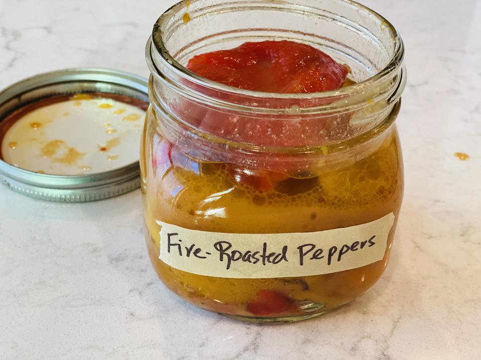A jar of red-wine vinaigrette marinated Fire-Roasted Peppers is in opened to show the sweet red and yellow roasted peppers in a photo by Elizabeth Karmel. 