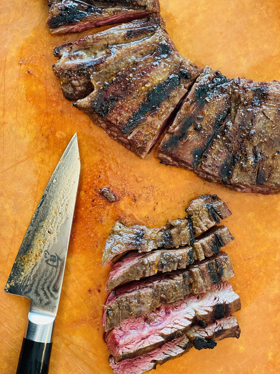 For perfectly carved skirt steak that is tender, cut steak in 4-inch pieces and slice the pieces vertically to carve the steak against the grain every time. This photograph by Elizabeth Karmel shows how to cut the meat in pieces and carve the pieces vertically.