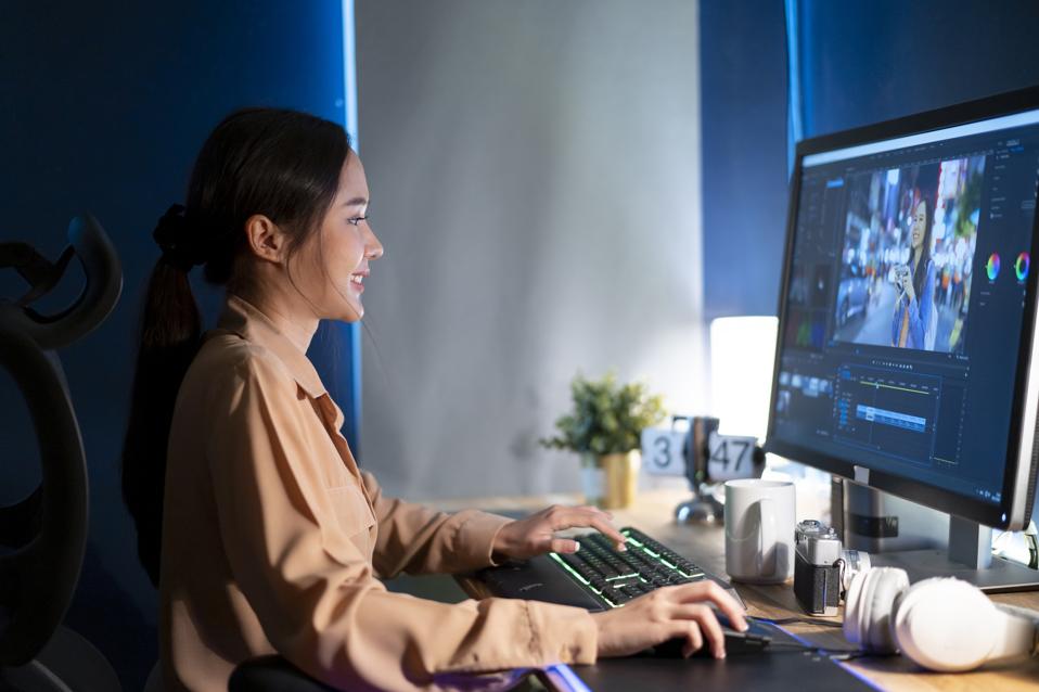 Hermosa editora de video femenina trabaja con imágenes en su computadora personal, trabaja en Creative Office Studio.