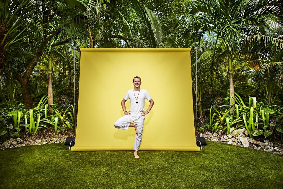 Ryan Breslow standing in a yoga post in front of a yellow background