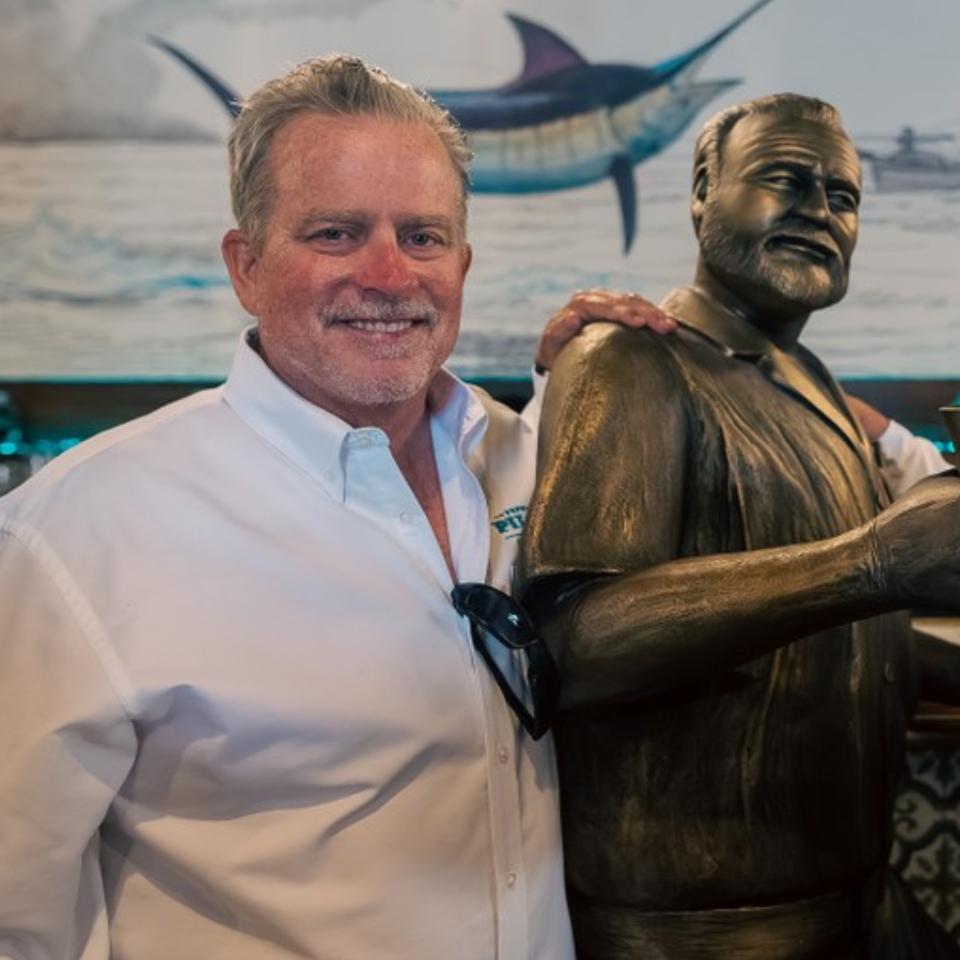 Papa's Pilar founder and CEO, Steve Groth, at the distillery's bar with the resident statue of Papa Hemingway.