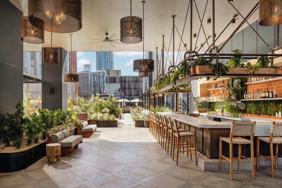 Wax Myrtle’s outdoor area includes a lush pool deck and a bar surrounded by greenery.