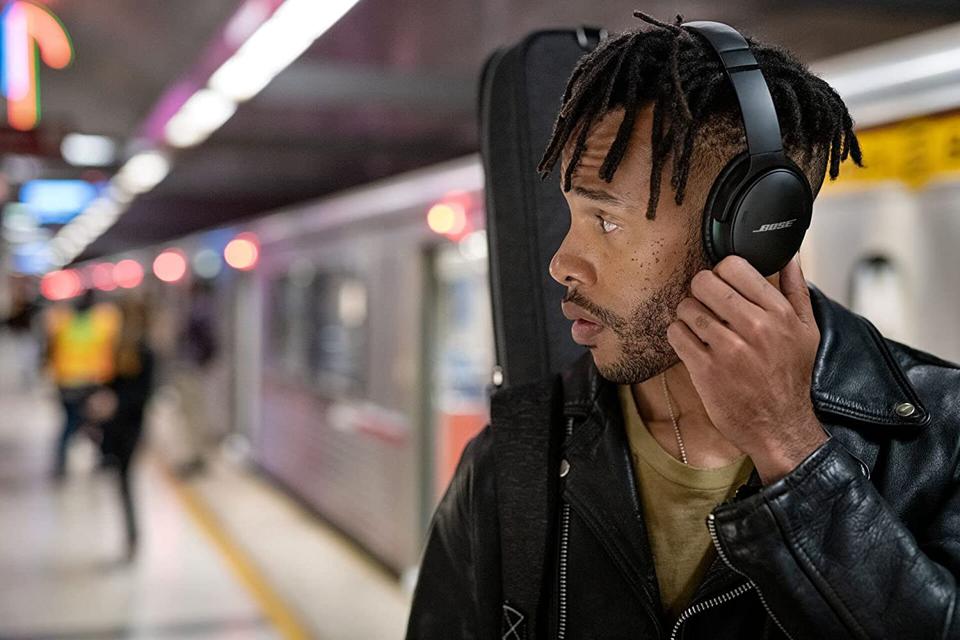 A man next to the subway wearing a pair of Bose QuietComfort 45 Bluetooth Headphones