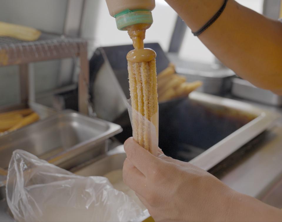 Stuffing a churro in a street cart