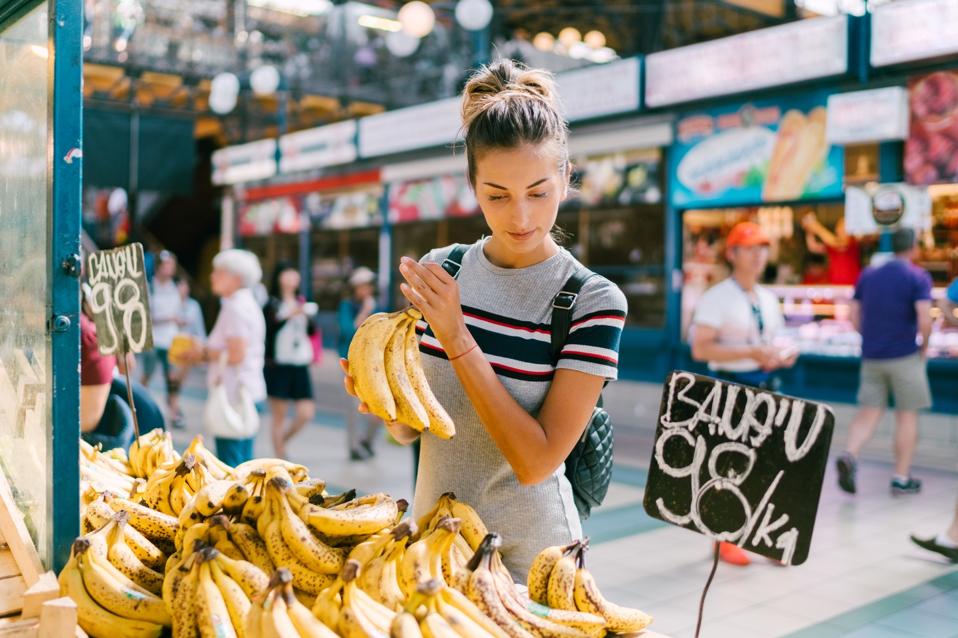 Young woman buying bananas at the market