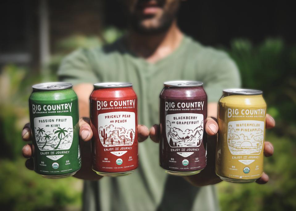 A man holding cans of Big Country Hard Seltzer