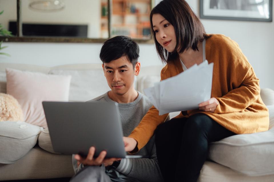 Young couple looking at laptop and papers