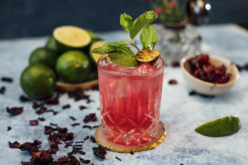 Cocktail glass with fresh limes and hibiscus flowers