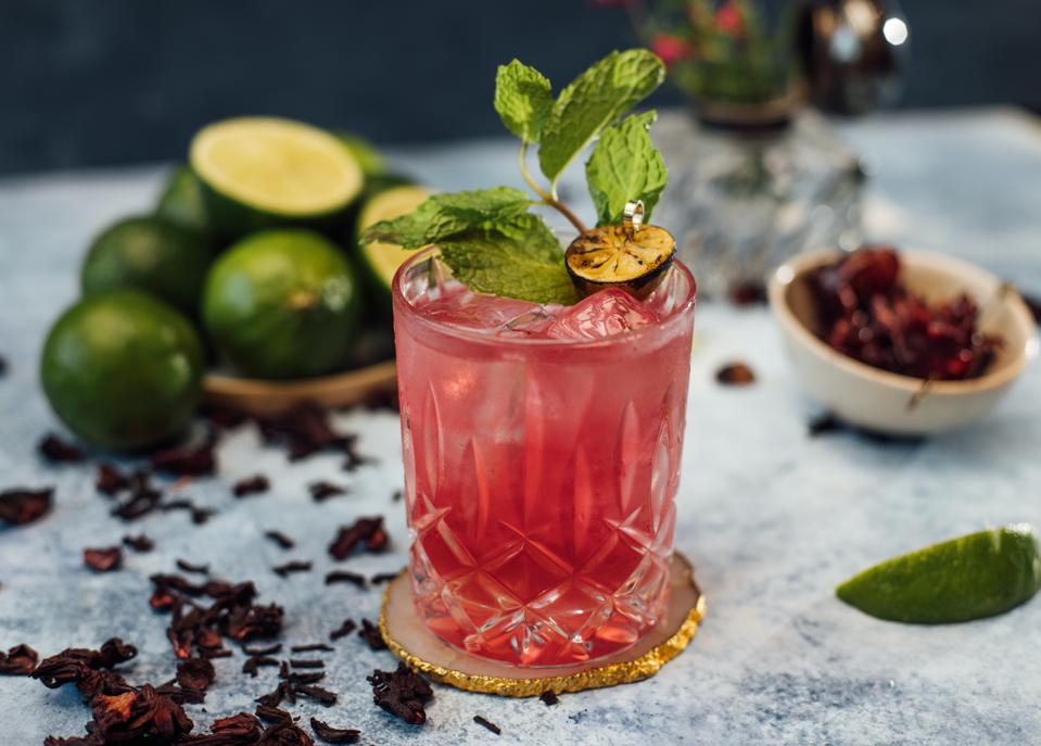 Cocktail glass with fresh limes and hibiscus flowers