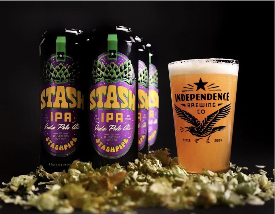 16oz cans of Stash IPA and an Independence branded pint glass full of the beer.