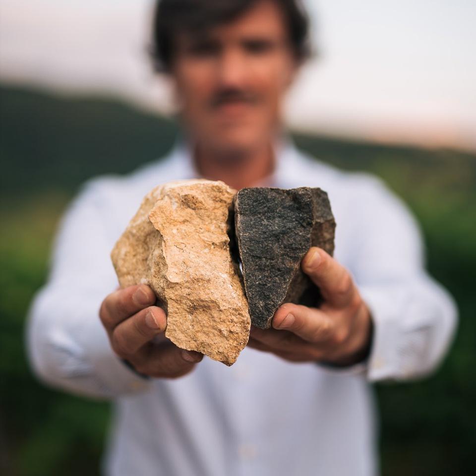 Andrea Lonardi holding up white limestone and red limestone from Bertani's vineyards   Cantine Bertani
