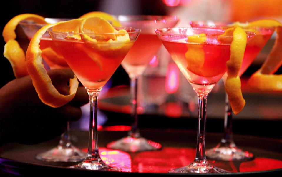 Martini glasses full of pink liquid and garnished with citrus peel