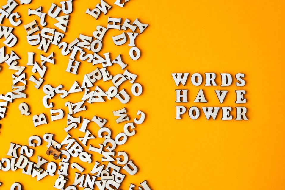 Quote WORDS HAVE POWER made out of wooden letters on bright yellow background.