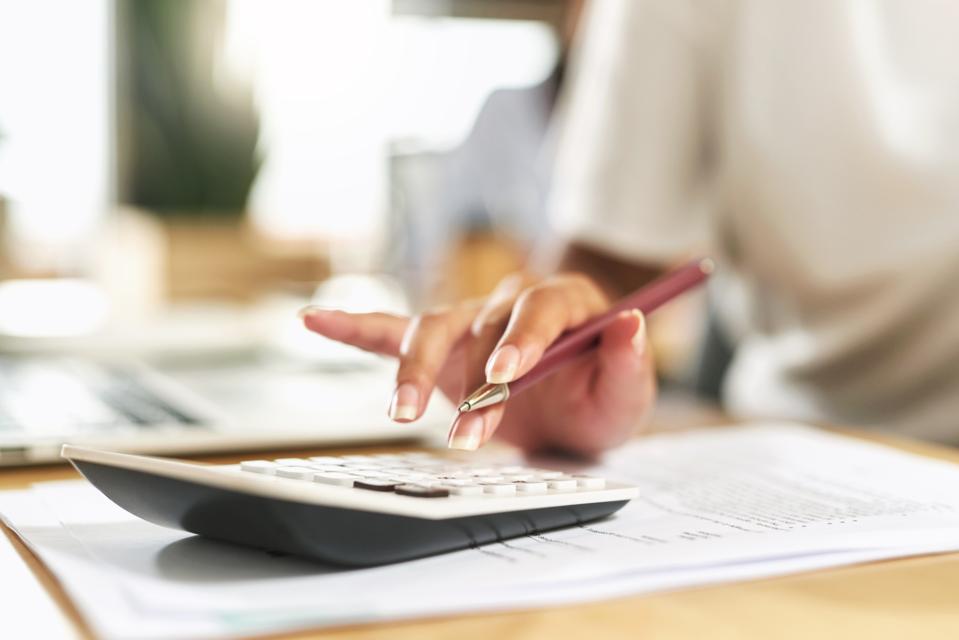 Foto de una mujer de negocios usando una calculadora para presupuestar sus finanzas