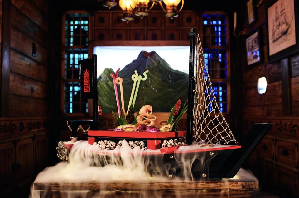 Tiki Tatsu-Ya’s “Skeleton Cruise” cocktail served in a boat-shaped vessel surrounded by dry ice.