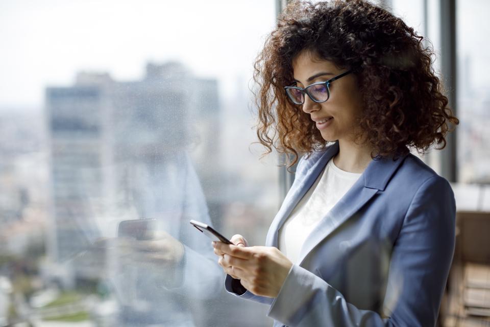 Joven empresaria usando un teléfono inteligente en la oficina