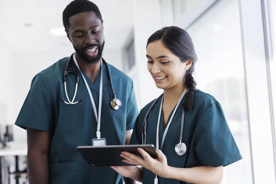 Dos médicos mirando una tableta digital en el pasillo del hospital