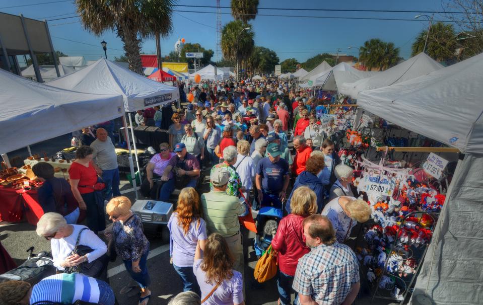 A festive crowd wandering amid vendor tents at the Kumquat Festival.