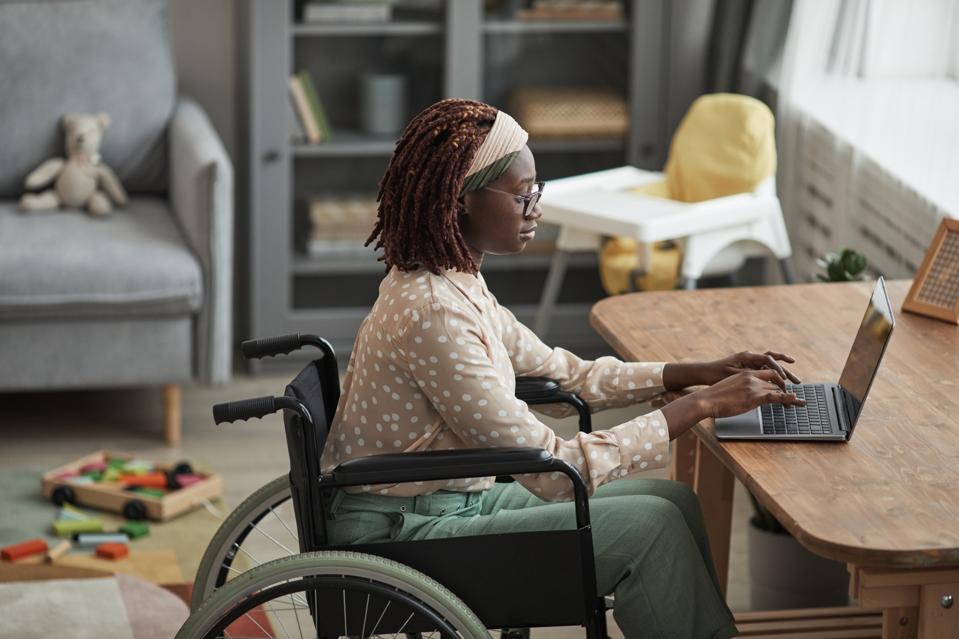 Mujer afroamericana en silla de ruedas usando computadora en casa