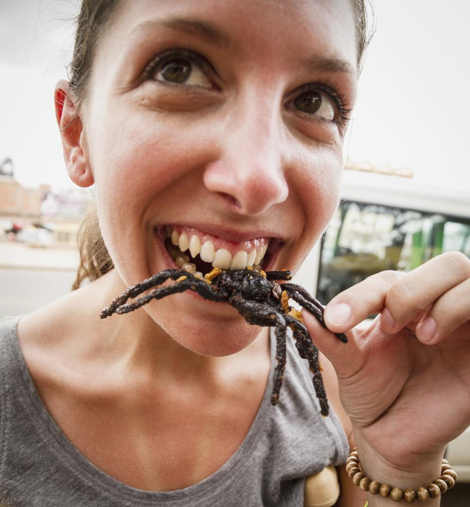 Cambodia, Young woman eating fried tarantula spiders