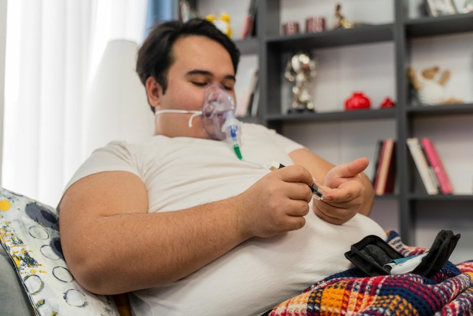 Adolescente con obesidad, con suplemento de oxígeno. Comprobación del nivel de azúcar en la sangre.
