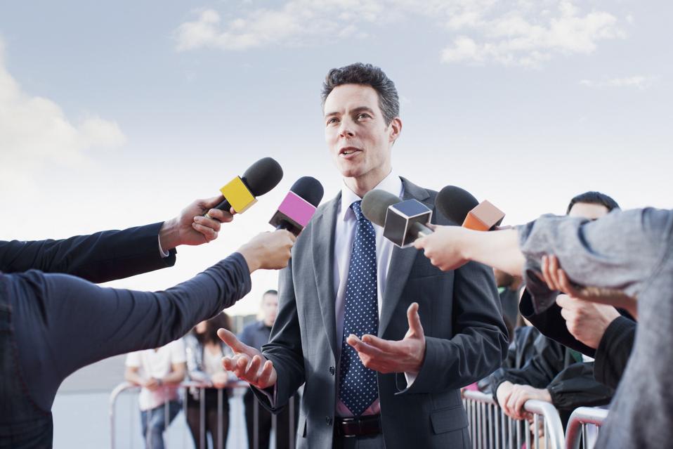 Politician talking into reporters' microphones
