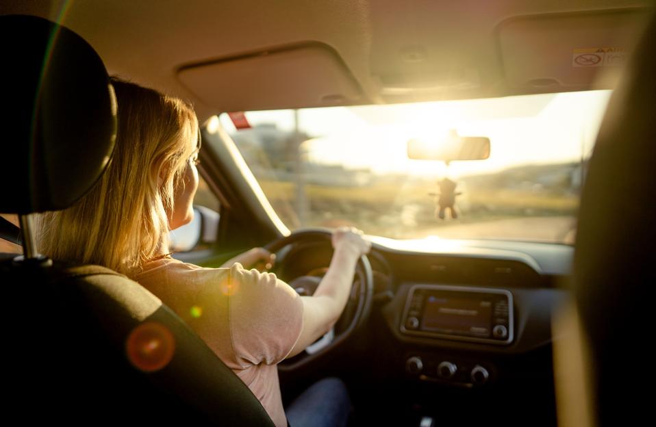 Mujer conduciendo su coche por una carretera en una tarde de verano