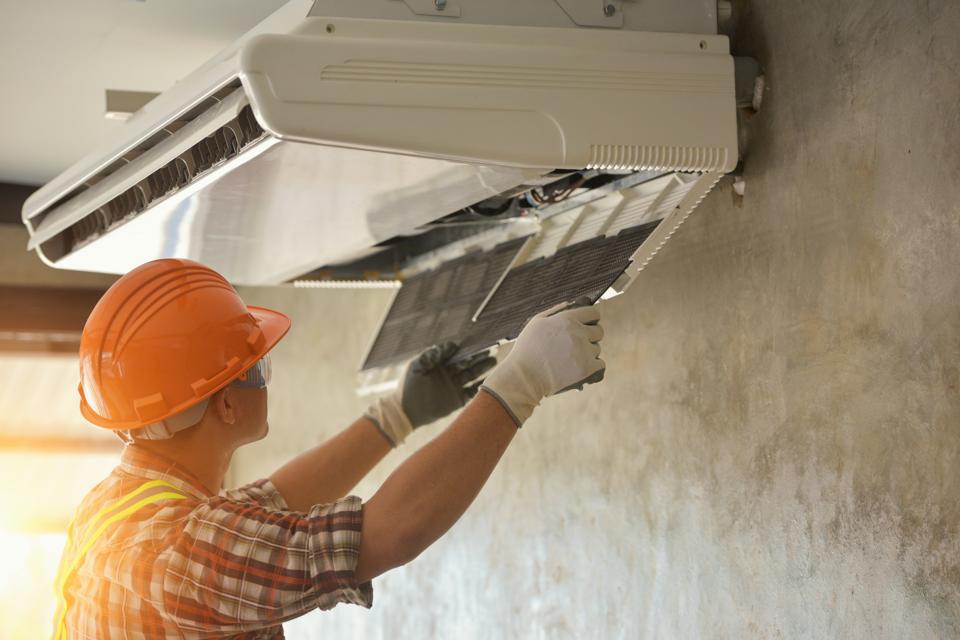 Los reparadores de aire acondicionado trabajan en la unidad doméstica