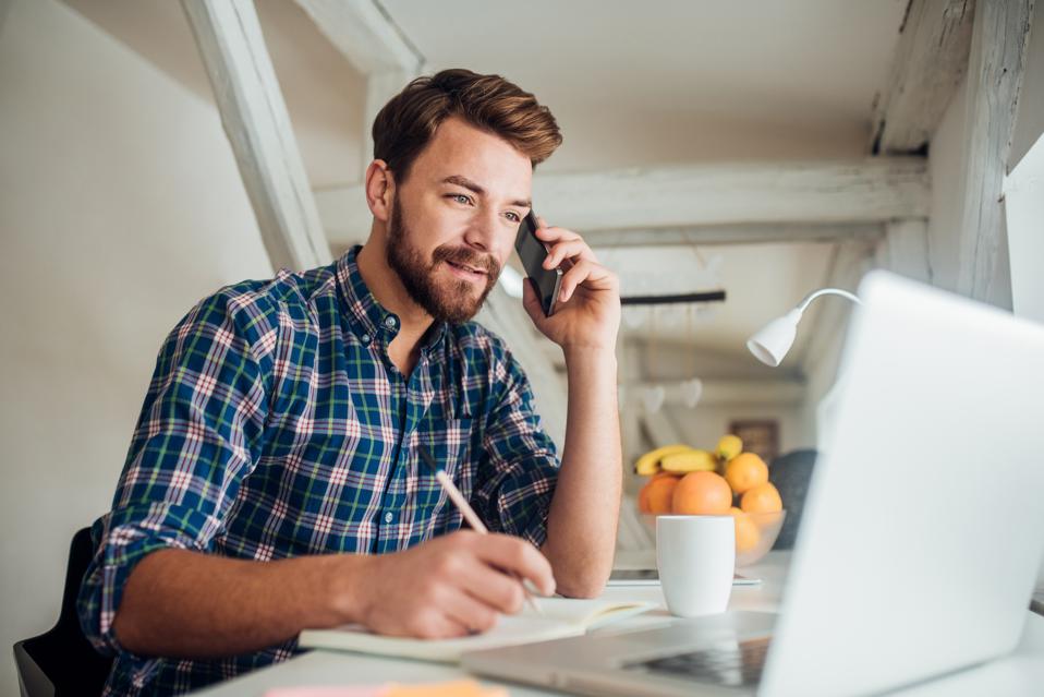 Hombre escribiendo y hablando por teléfono