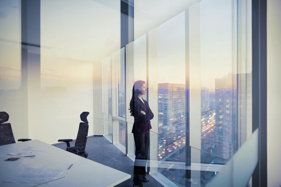 La empresaria mirando por la ventana en la sala de reuniones