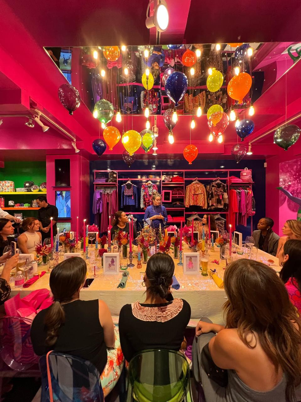 Zara Terez Tisch giving a speech to journalists sitting around a table at the Terez store on Lexington Avenue