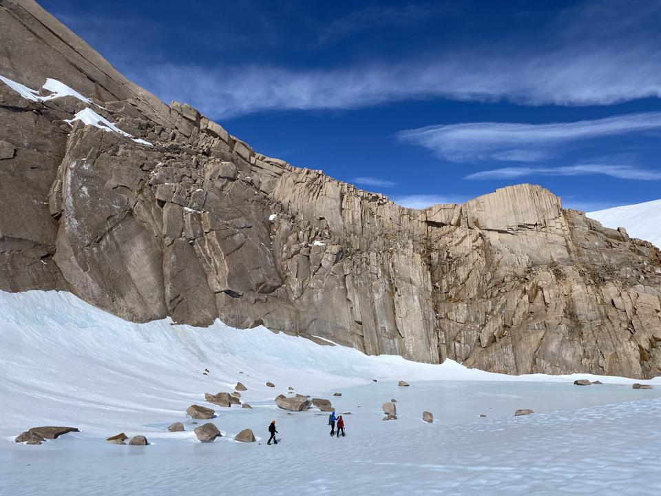 The team hiking past rock formations in Antarctica.