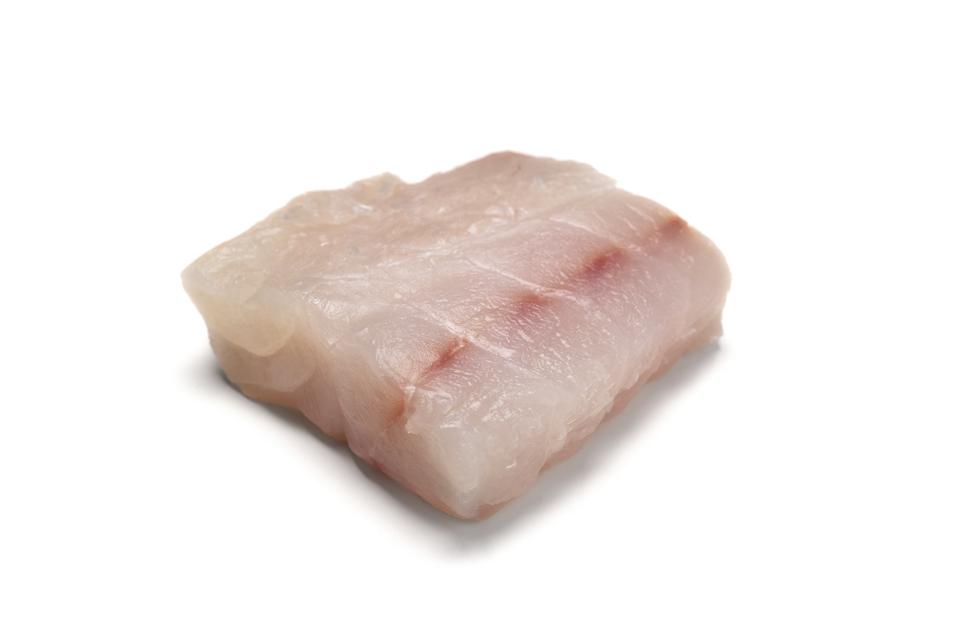 Filete de pescado de mero crudo sobre fondo blanco.