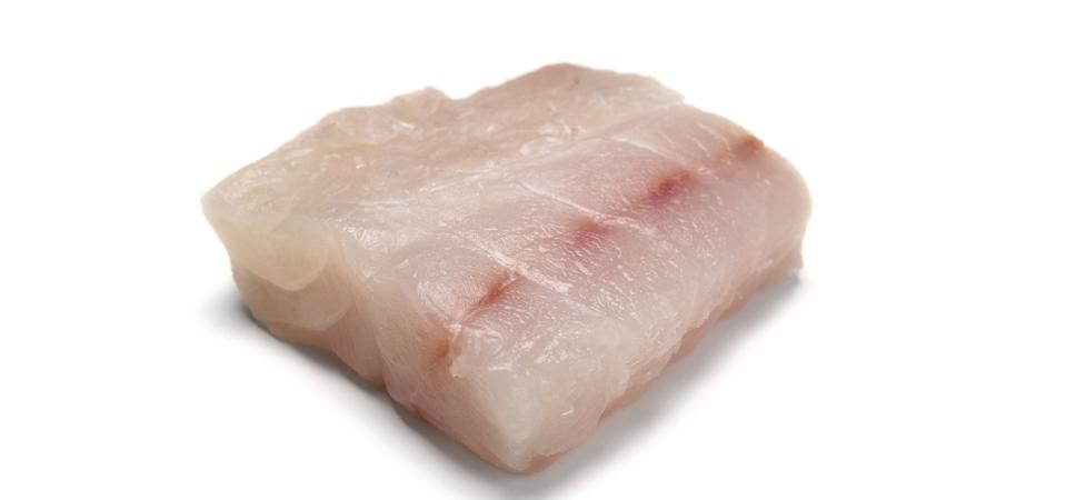 Filete de pescado de mero crudo sobre fondo blanco.