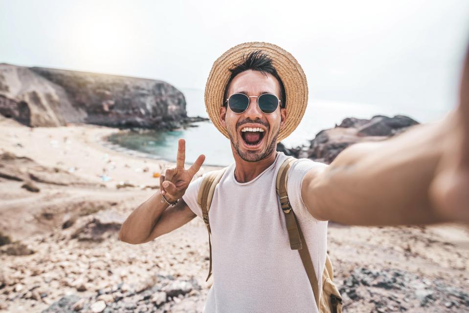 Joven con mochila tomando un retrato de selfie en una montaña - Enfoque milenario en el progreso, no en los resultados