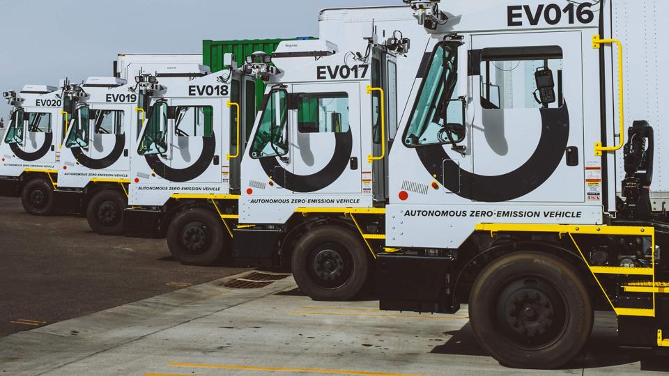 Automated electric yard trucks at a logistics facility.