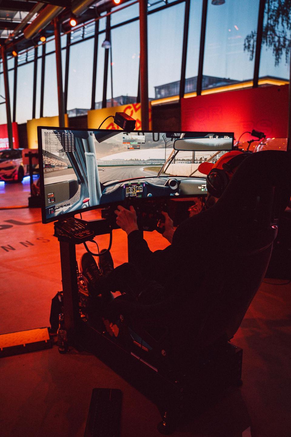 Людина їде в Rennsport із вигнутим екраном, кермом і педалями.